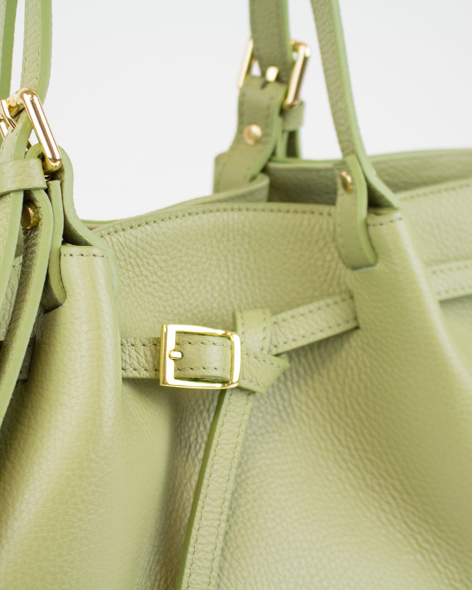 Close-up of olive-green Italian leather handbag showcasing textured finish and gold-tone hardware details.