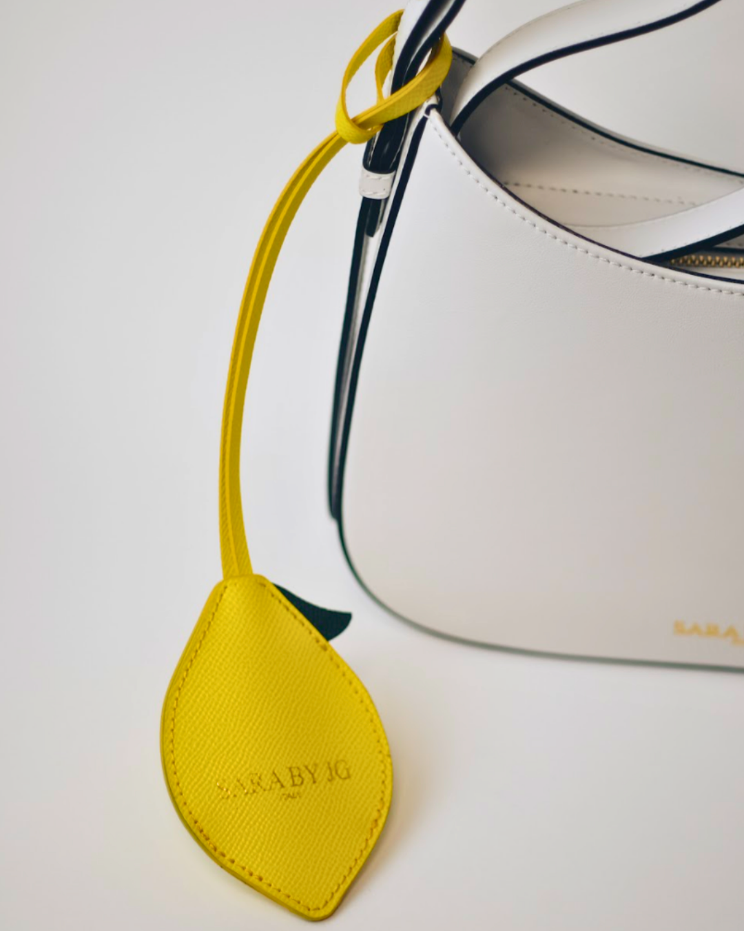 Yellow leather tag with 'Cala By Jo' branding on a white background